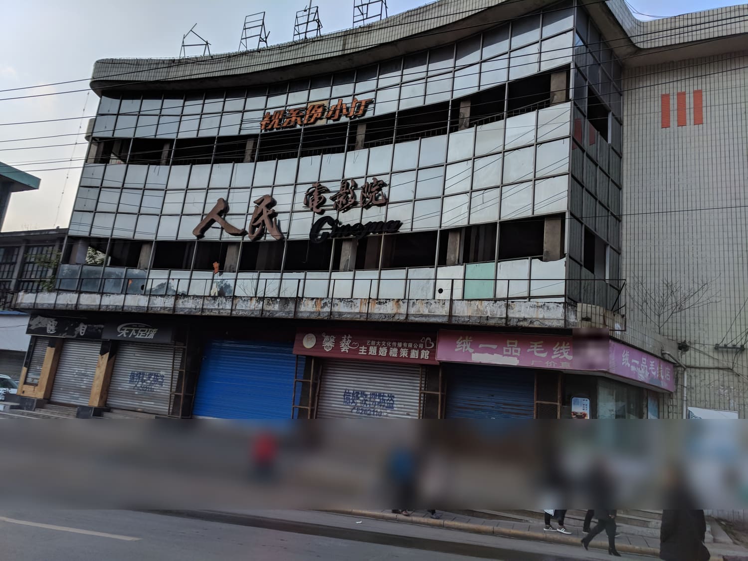 解放路上歇业的人民电影院旧楼，楼下行人往来